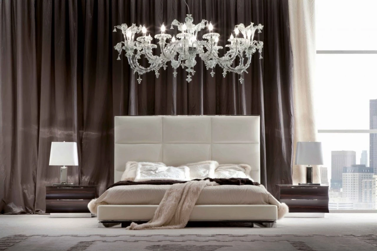 Bed with a tall padded headboard under a glass chandelier, luxury Italian furniture in London